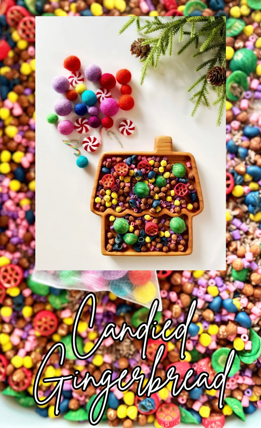 Wooden tray shaped like a gingerbread house filled with colorful beads and surrounded by pom-poms and greenery on white surface