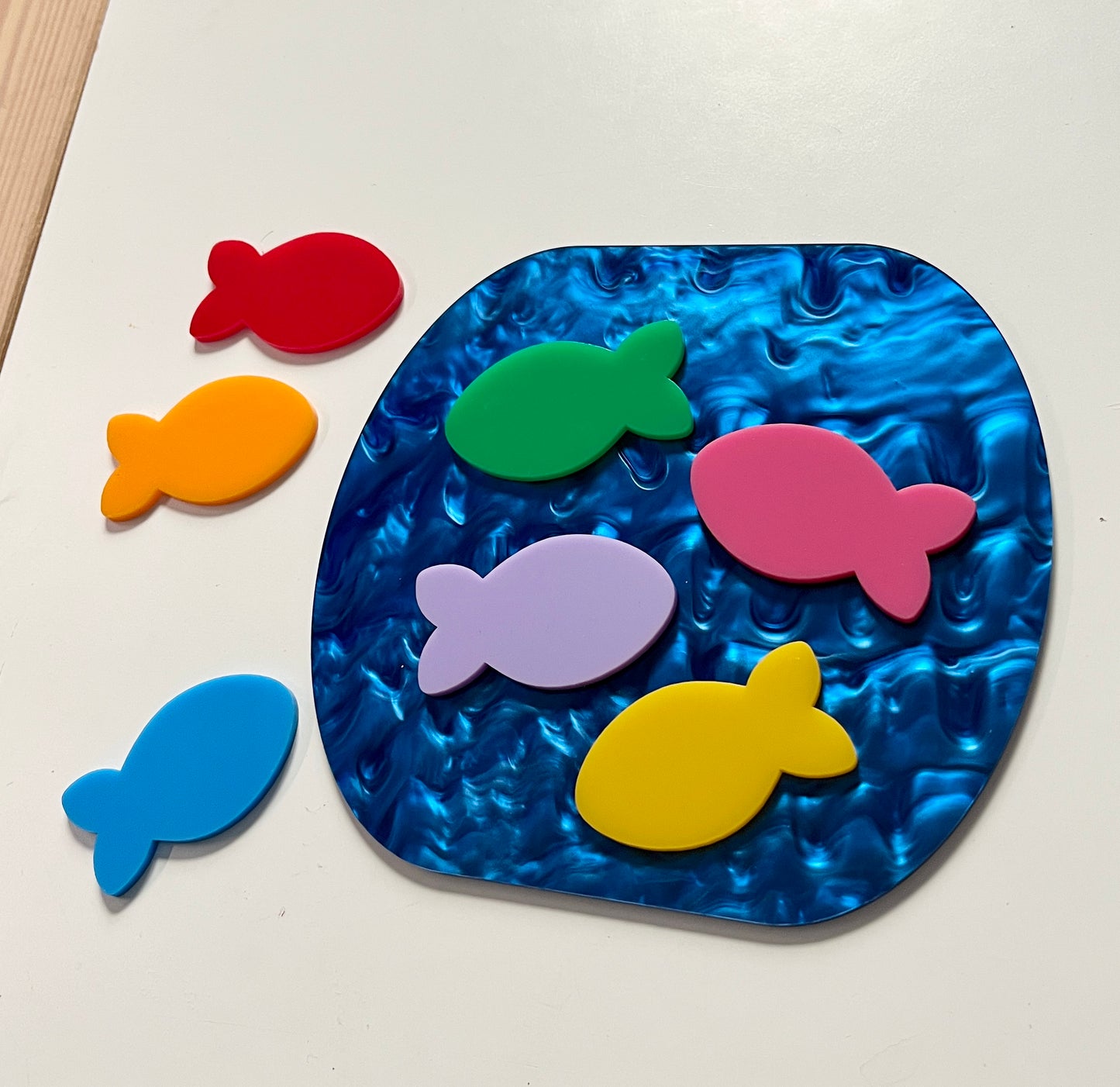 Colorful dry erase fish around a marble dry erase pond on a white background