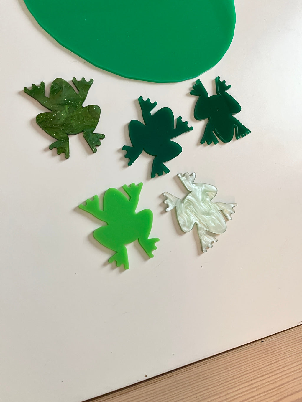 Little Dry Erasables - Frogs featuring translucent and solid green frog-shaped pieces with a green lilypad on a white surface, handcrafted homeschool education resources.