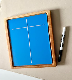 Rectangular wooden-framed blue board with white cross lines next to a black and white marker on beige surface