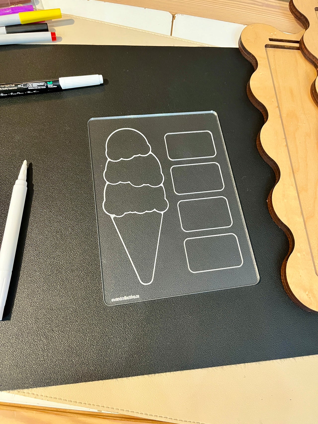 Clear acrylic board with ice cream cone and four rectangular sections on black mat beside white markers and wooden shapes