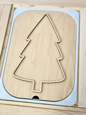 Light unfinished plywood puzzle piece shaped like a simplified pine tree with smooth cut edges in a wooden frame
