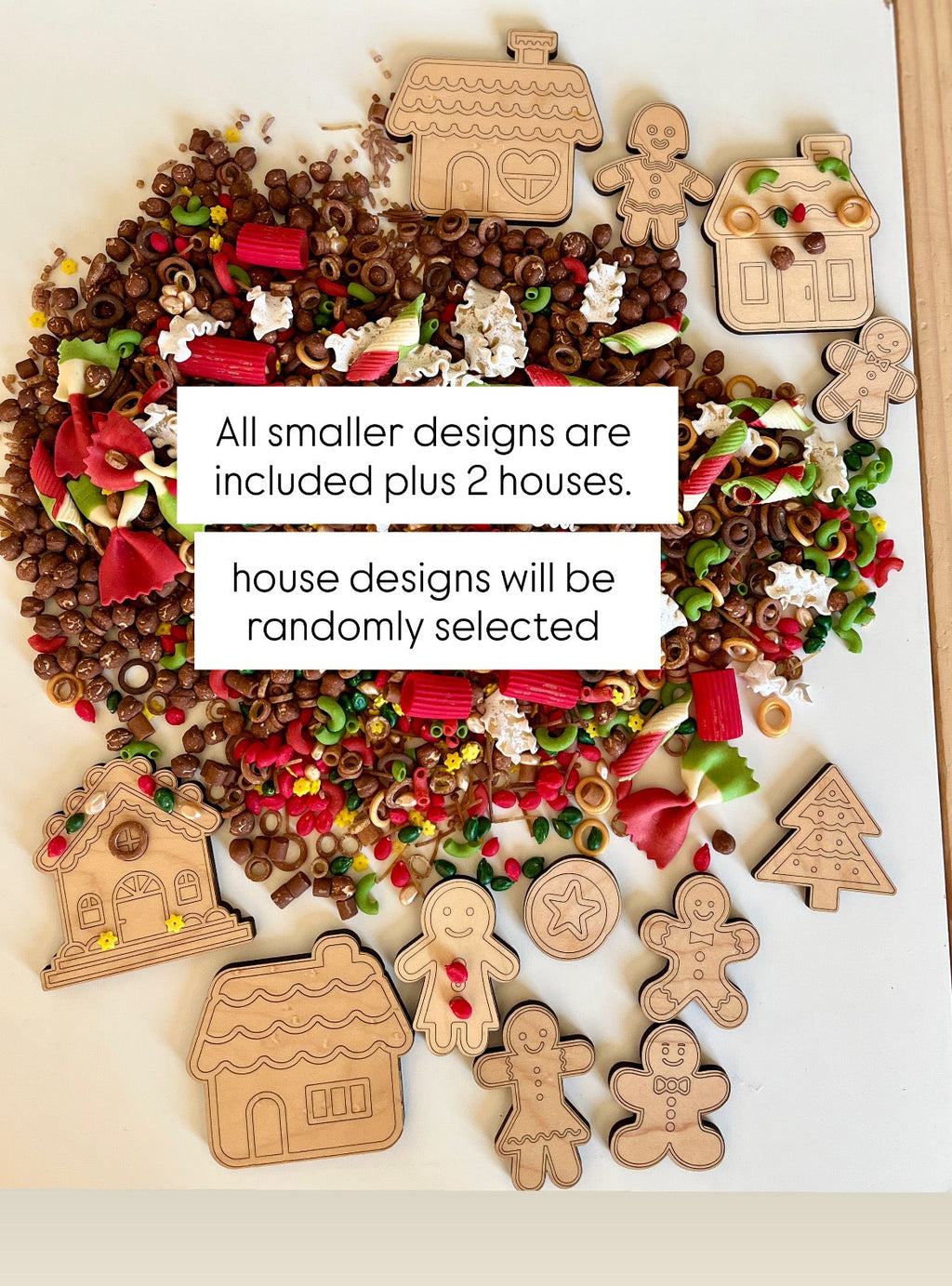 Wooden gingerbread and house shapes with colorful pasta and chocolate cereal pieces scattered on a white surface