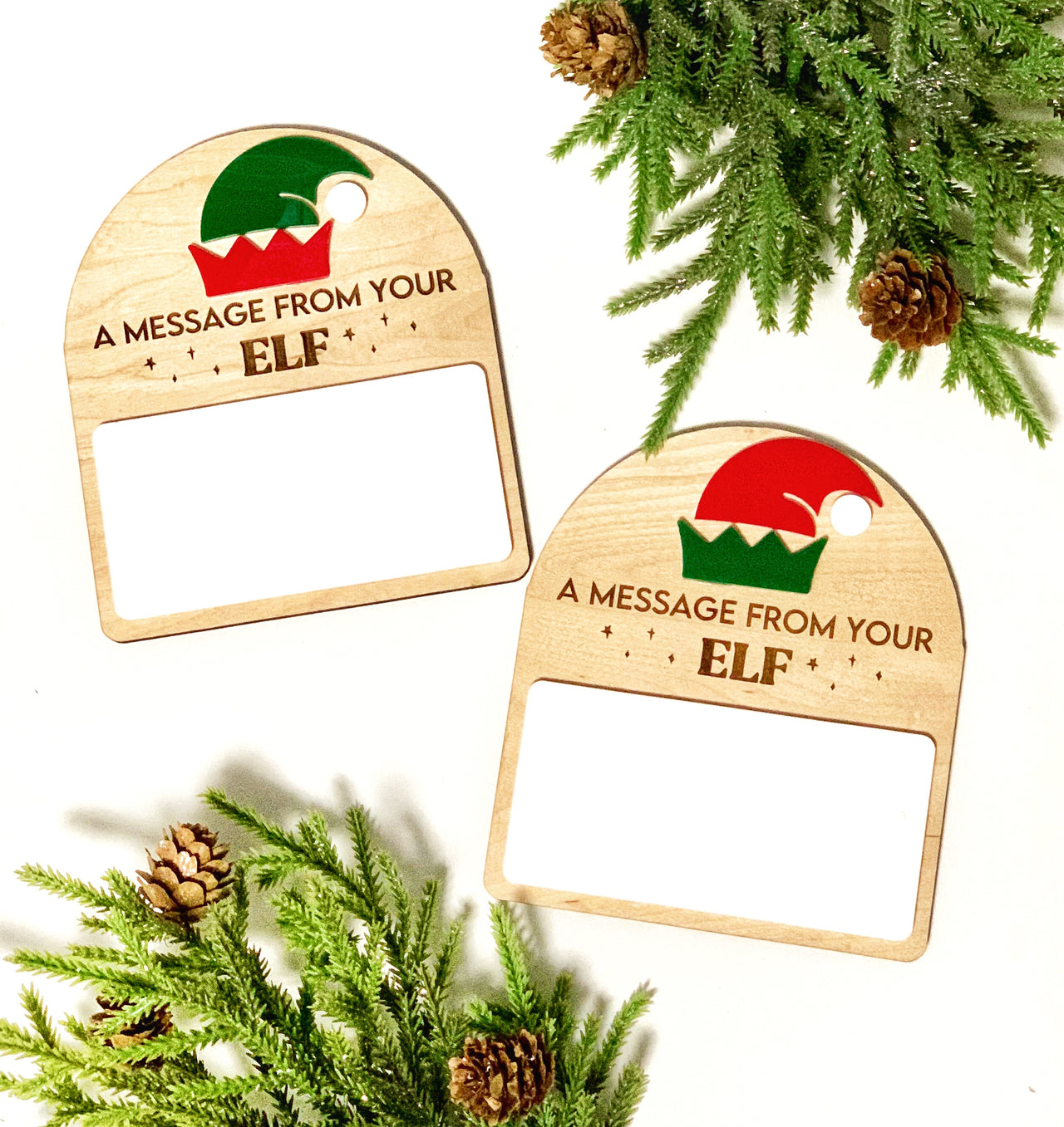 Two wooden note holders with elf hat designs and the text "A message from your ELF" surrounded by pine branches and cones