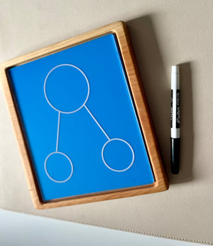 Wooden framed blue drawing board with three connected circles and black and white marker on beige surface