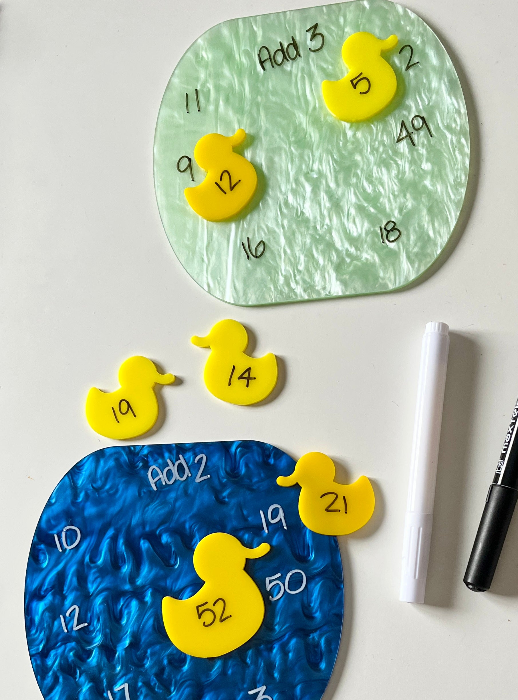 Dry Erase educational tool with dry erase ducks and dry erase ponds on a white background with markers.  Currently being used for math