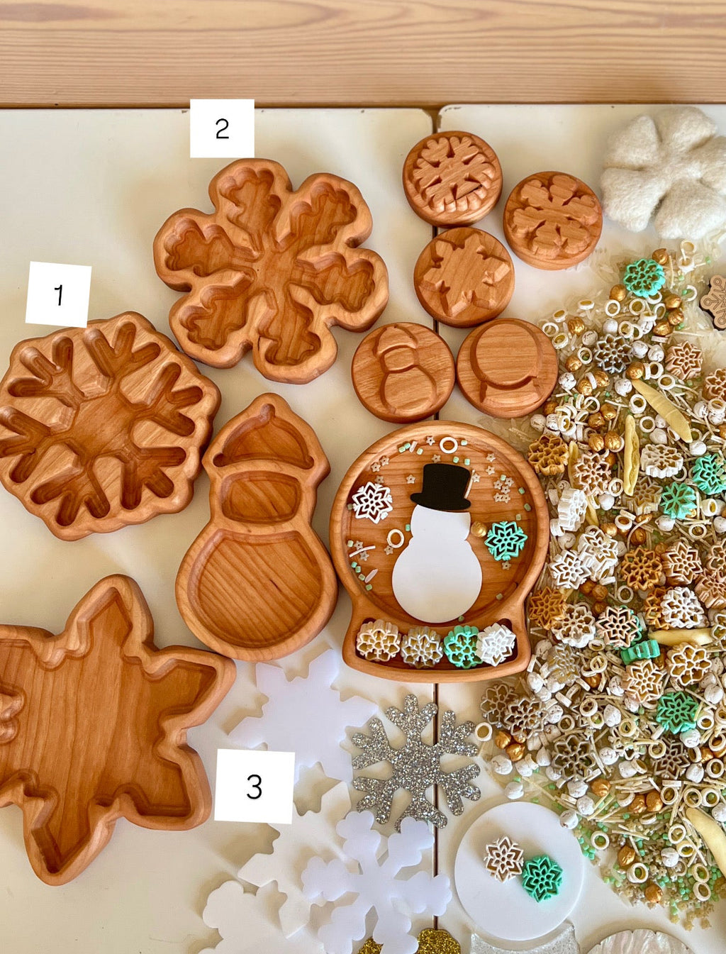 Assortment of carved wooden trays shaped like snowflakes, snowman, and round discs with winter-themed decorations on a table