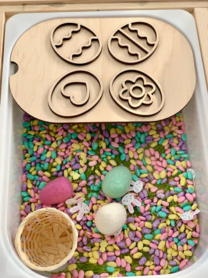 Small basket and pastel-colored sensory beans with felt eggs and wooden Easter egg stencil on top
