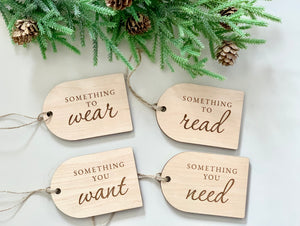 Set of four maple plywood Christmas gift tags engraved with "Something you want," "need," "read," and "wear" with pine decoration