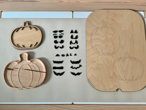Wooden pumpkin-shaped inserts and various black eyebrow and mouth pieces arranged on a beige surface next to pumpkin outlines