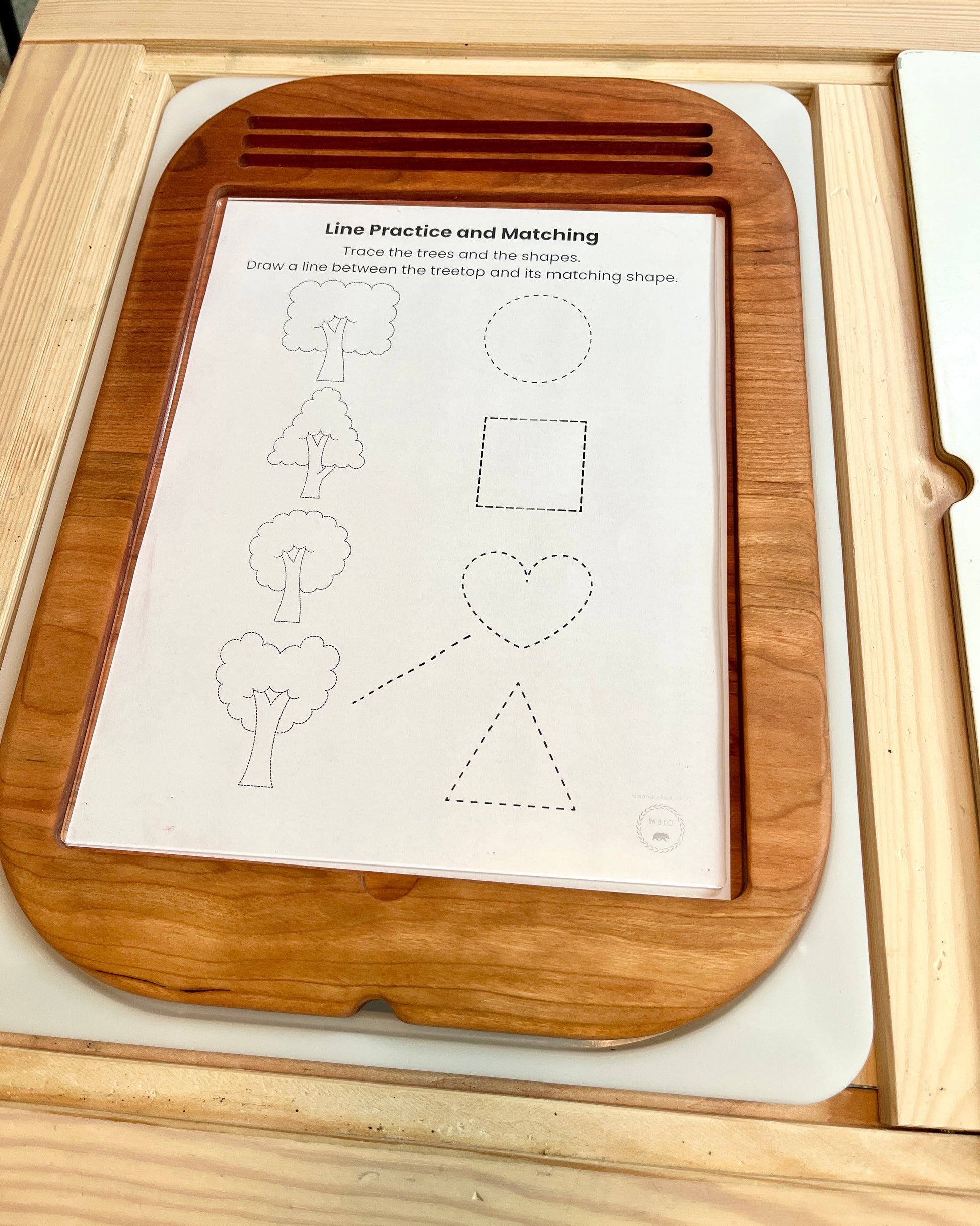 Wooden educational toy with a tracing sheet on a light wood surface
