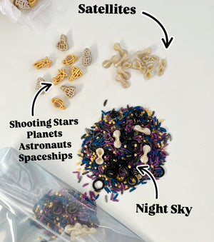 Space-themed pasta shapes including planets, stars, astronauts, and spaceships with mixed colored rice sensory set