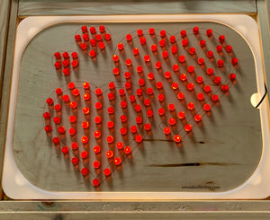 Lighted wooden board with four heart shapes outlined by glowing red pegs on a natural wood background.