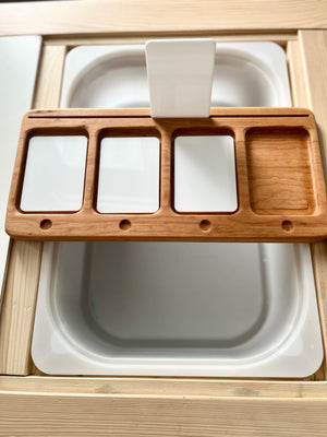 Rectangular wooden organizer with four compartments resting on a white surface with a vertical white plastic handle in the center