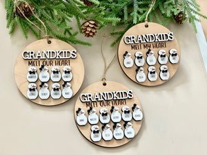 Three round wooden Christmas ornaments with "Grandkids Melt Our Heart" and personalized snowperson figures hanging on greenery background