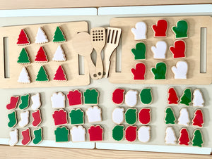 Wooden cookie sheet with red, green, and white felt cookies and matching wooden utensils on a white table