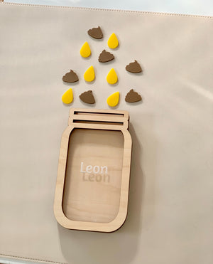 Personalized wooden reward jar with name Leon surrounded by yellow and brown wooden tokens on beige surface