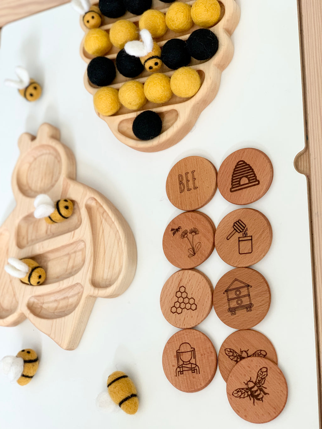 Bee themed memory game with wooden engraved coins, felt bee pieces, and natural wood bee-shaped trays on white surface