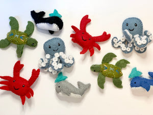 Collection of handmade felt sea creatures including octopus, crab, turtle, whale, orca, and shark on white background