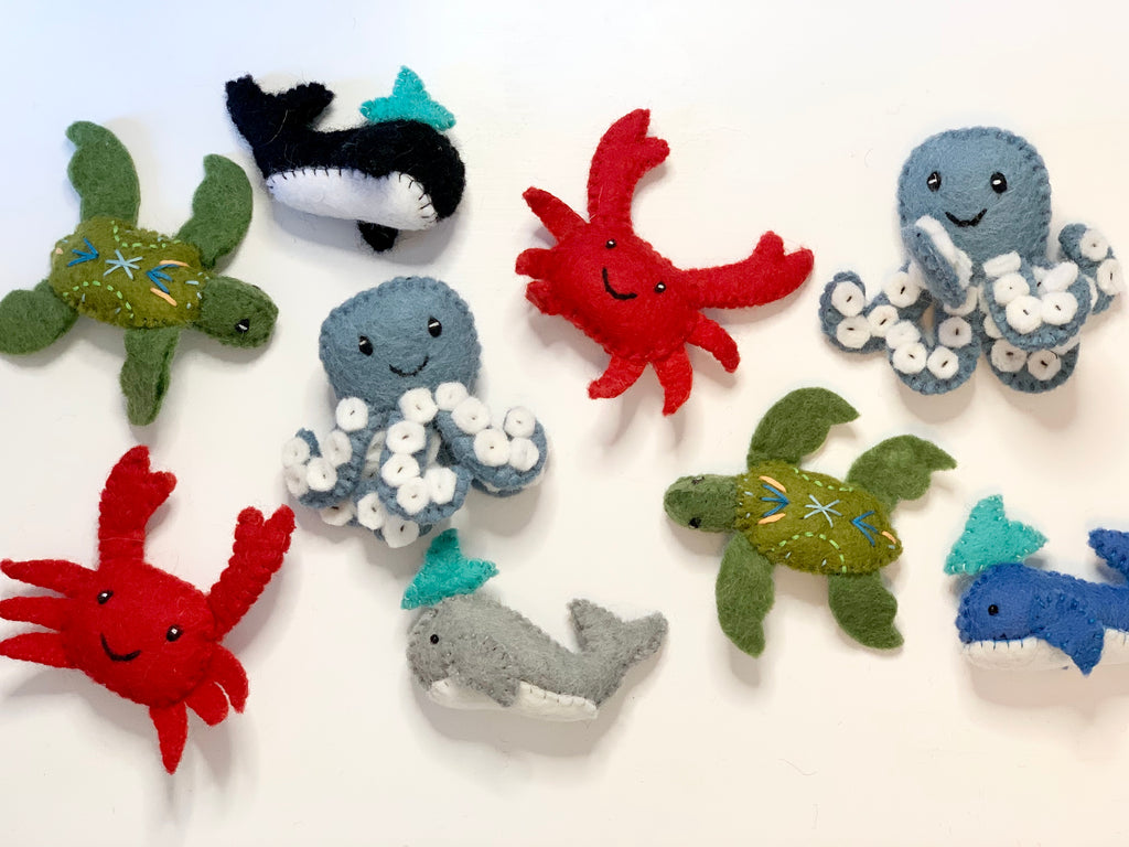 Collection of handmade felt sea creatures including octopus, crab, turtle, whale, orca, and shark on white background