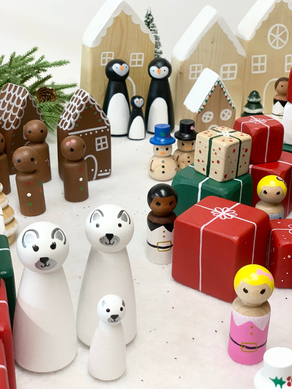 Made to order wooden polar bear and penguin family figurines with holiday-themed wooden houses and gift boxes background