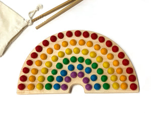 Canadian cherry hardwood rainbow sorting board with smooth engraved holes and colorful felt balls on white background