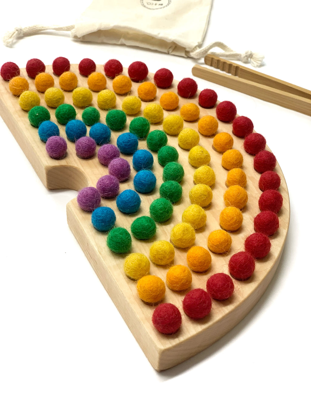 Rainbow shaped Canadian cherry hardwood sorting board with colorful felt balls and wooden tweezers on white background