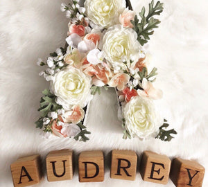 Natural wooden 1.5-inch alphabet blocks with engraved letters spelling AUDREY on white fabric background