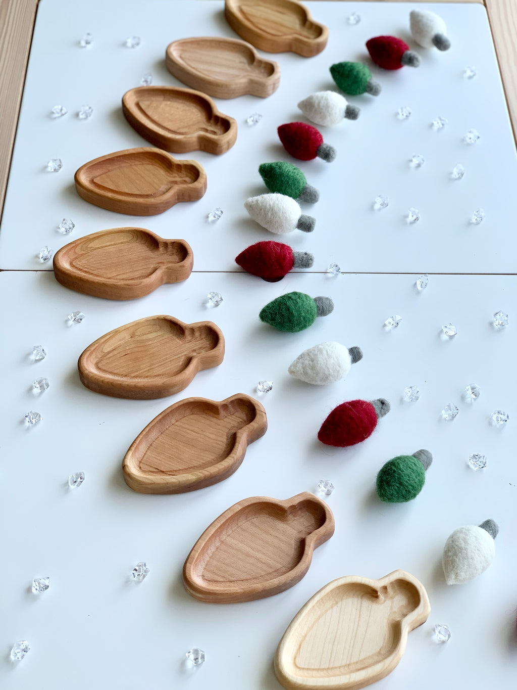 Set of small lightbulb-shaped wooden plates with red, green, and white felted lightbulb decorations on white surface