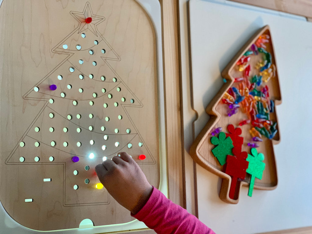 Wooden Christmas tree peg insert with light-up holes and colorful acrylic present pegs on natural wood surface