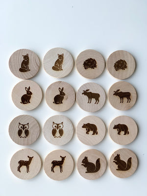 Natural wooden memory game discs with engraved woodland animals including fox, hedgehog, rabbit, moose, owl, bear, deer, and squirrel on white background