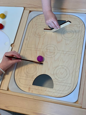 Wooden table top hockey Flisat insert with two hockey sticks and felt balls on wooden surface