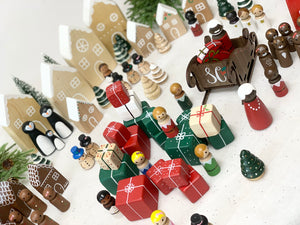 Hand-painted Christmas peg dolls with Santa, reindeer, gingerbread, presents, trees, and snowy village background