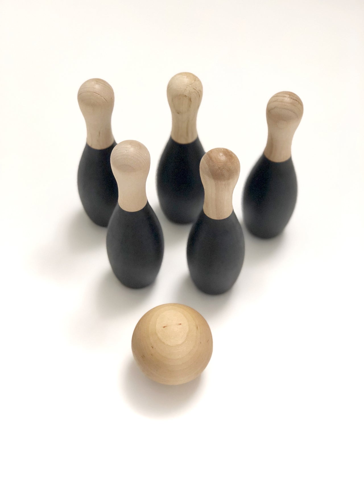 Natural wooden toddler bowling set with five black pins and one ball on white background