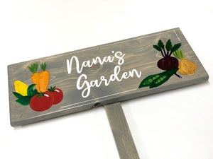 Large custom wooden vegetable garden sign painted gray with white cursive letters and colorful vegetable illustrations on wood grain background