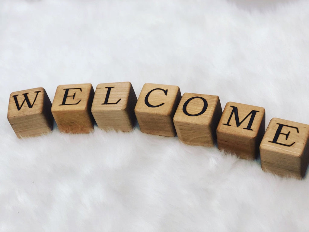 Custom 2-inch wooden blocks spelling the word WELCOME on a soft white surface background