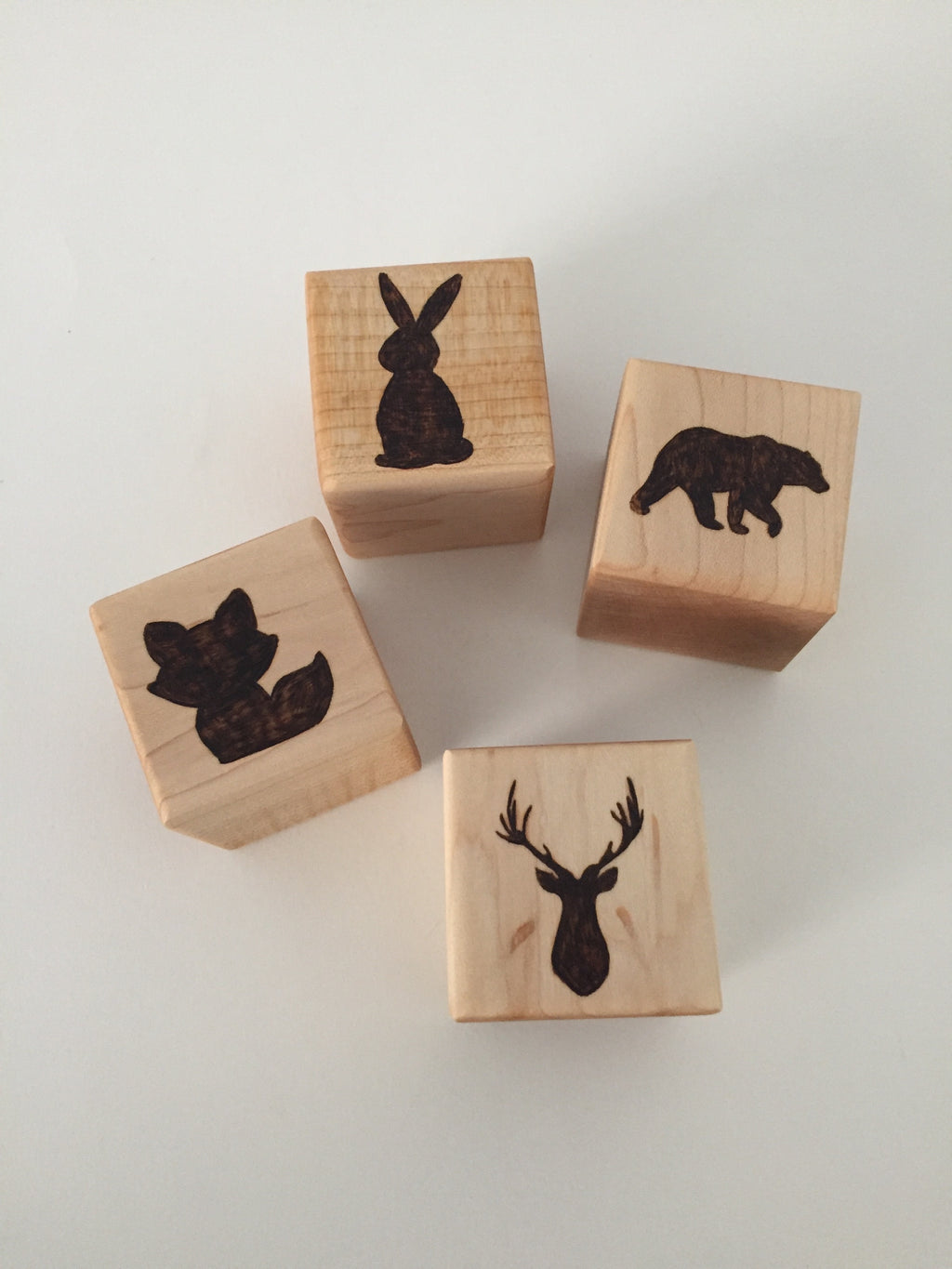 Four 2-inch custom wood blocks with engraved animal silhouettes including a rabbit, bear, fox, and deer head