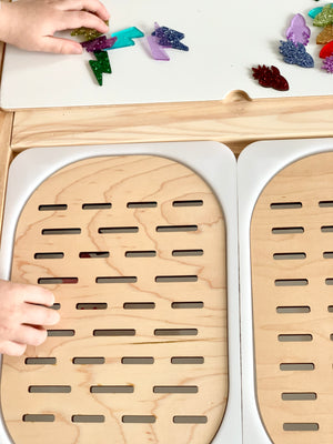 Wooden Slots Sorter Flisat table top insert with small slot openings and children's hands placing colorful resin shapes