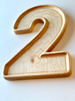 Large natural wooden number plate in the shape of digit 2 with smooth edges and visible wood grain texture on white background
