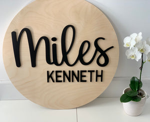 3D round wooden name sign with "Miles Kenneth" in black cursive and block letters on natural wood background