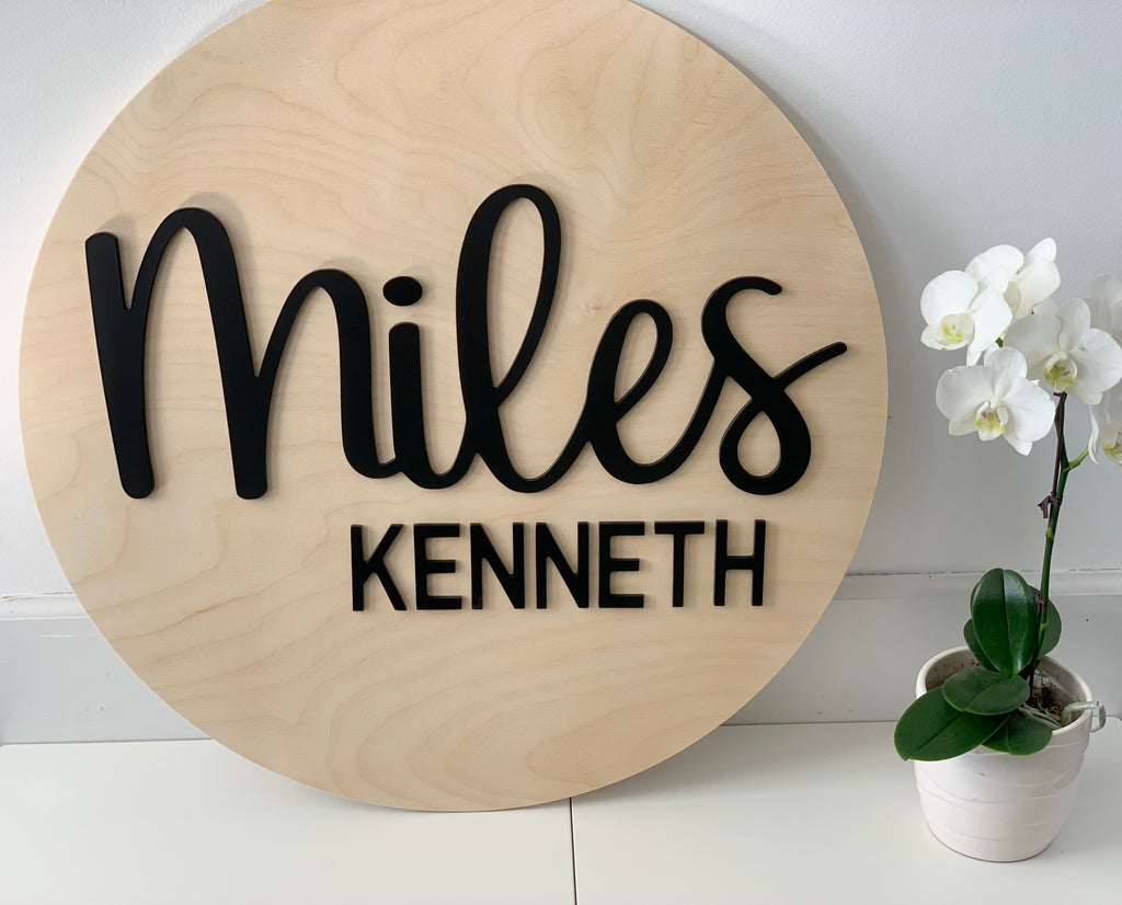3D round wooden name sign with "Miles Kenneth" in black cursive and block letters on natural wood background