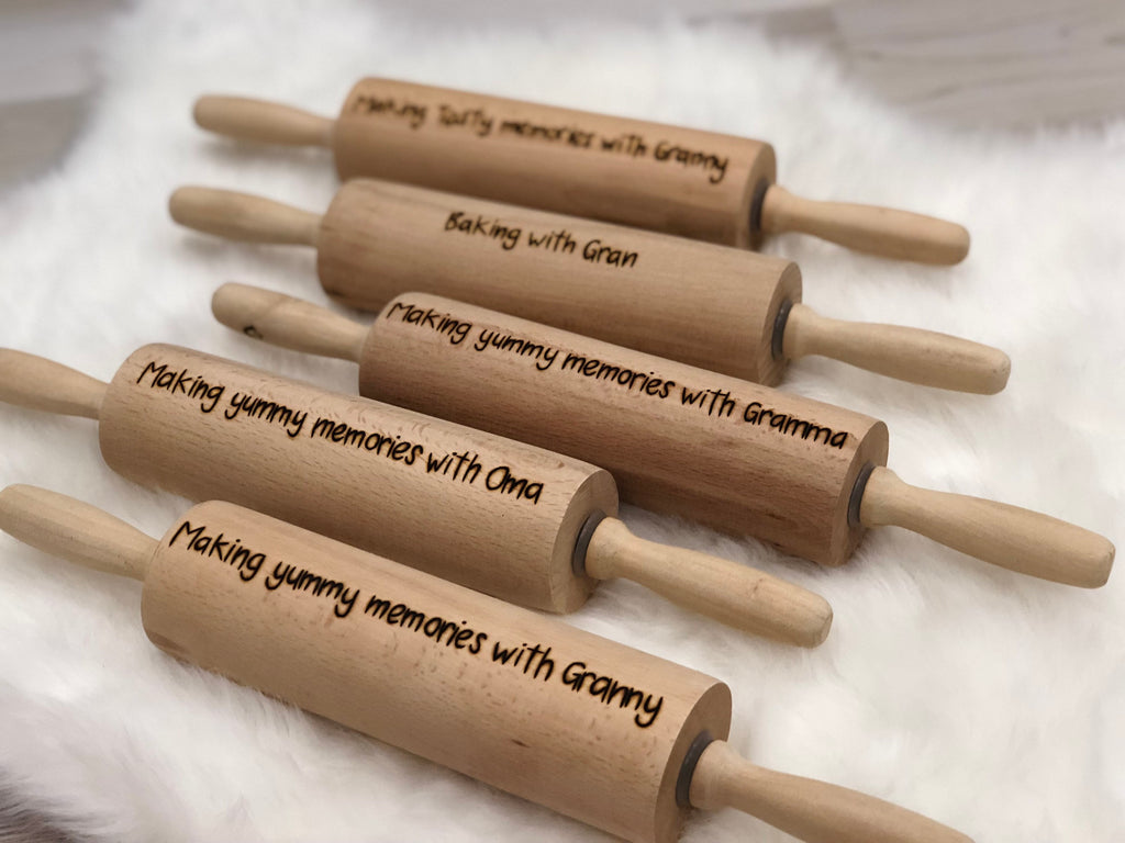 Set of personalized wooden rolling pins with custom wood burned messages on smooth natural wood surface