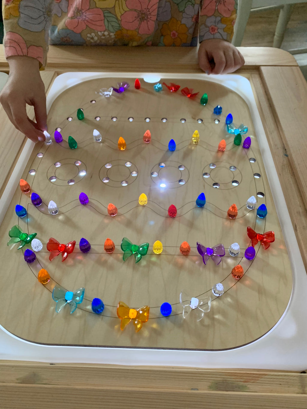 Light Up Easter Egg Flisat Insert with colorful light pegs arranged and a child’s hands placing a peg on wooden table