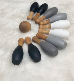 Monochrome 10-piece wooden bowling set with natural wood ball and black, gray, and white pins on soft fabric background