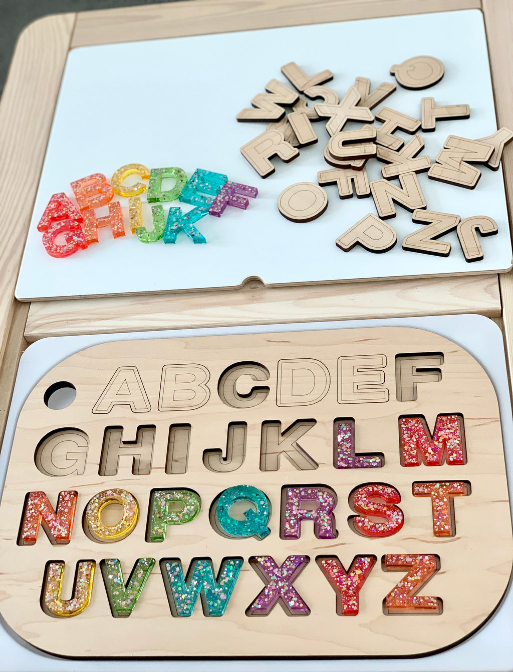 Wooden alphabet puzzle insert with colorful resin uppercase letters and loose wooden uppercase letters on white background