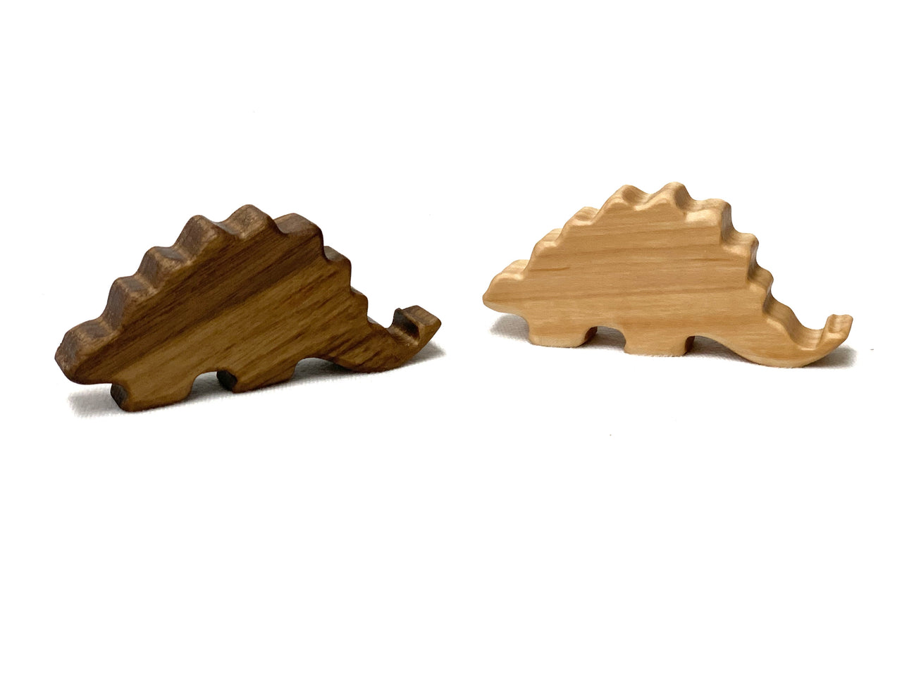 Two small Stegosaurus dinosaur wood toy figurines in dark and light natural wood on white background