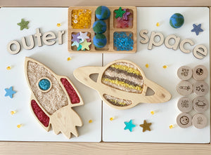 Large wooden outer space sensory play set with laser cut planets, stars, rocket, and letter tiles on light surface