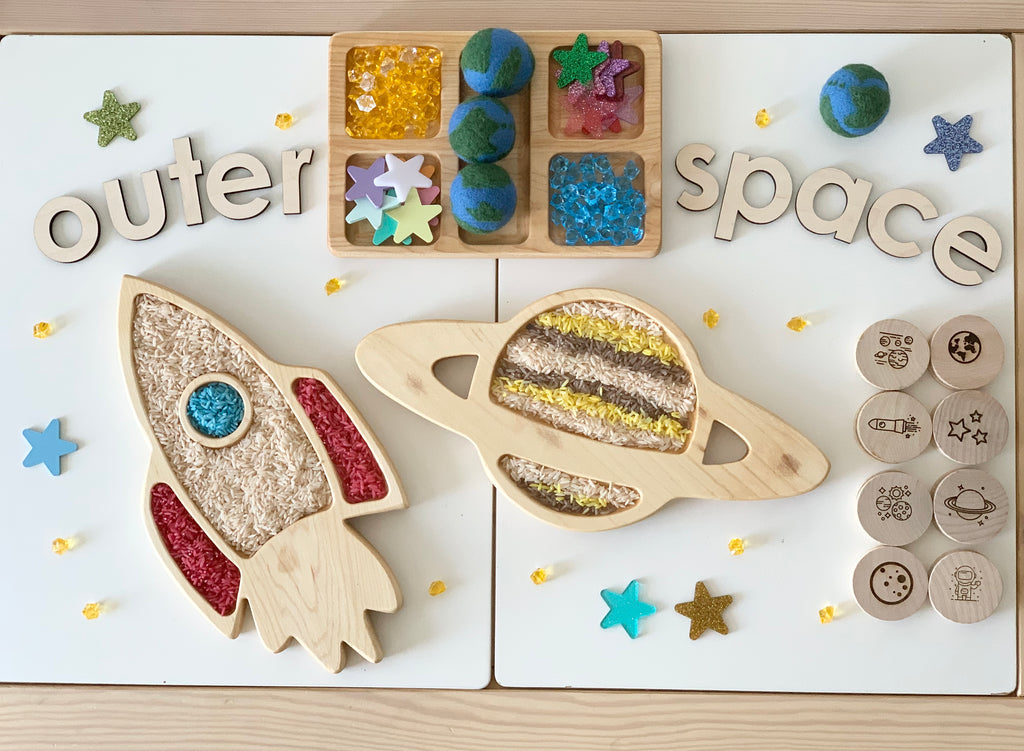 Large wooden outer space sensory play set with laser cut planets, stars, rocket, and letter tiles on light surface