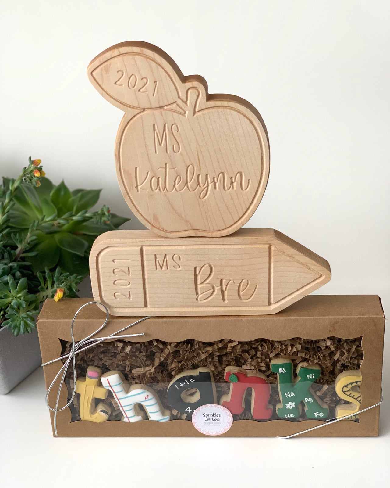 Personalized wooden apple and pencil name plates engraved with teacher names and year on natural wood background