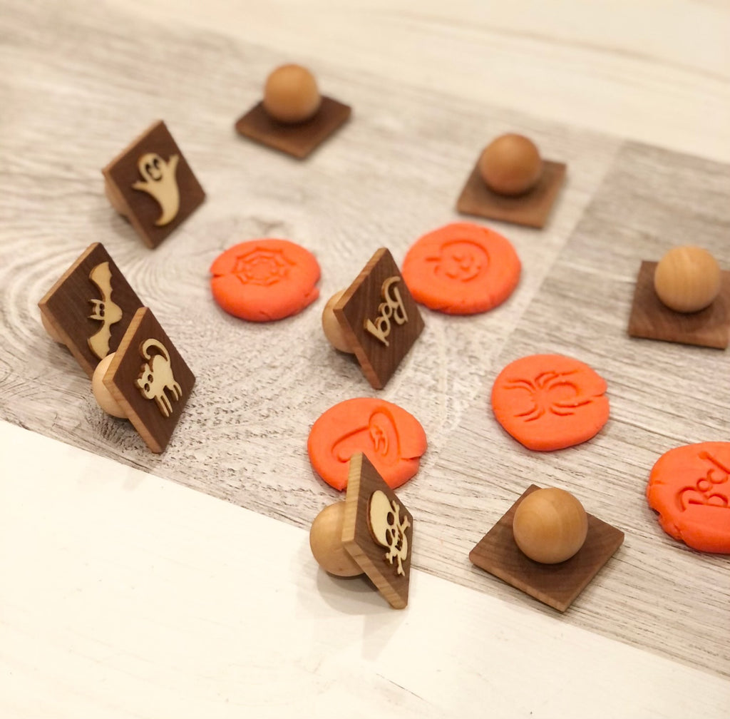 Set of small wooden Halloween play dough stamps with carved spooky designs on natural wood squares with round handles